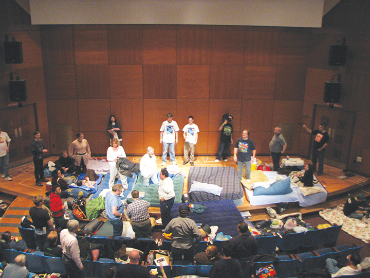 Students in Strosacker Auditorium preparing for Science Fiction Marathon by bringing mattresses and blankets to the stage